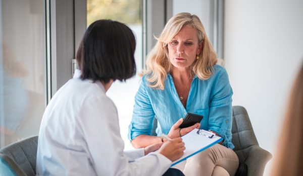 In a doctor's office with a mature Caucasian female patient and an Asian female doctor.